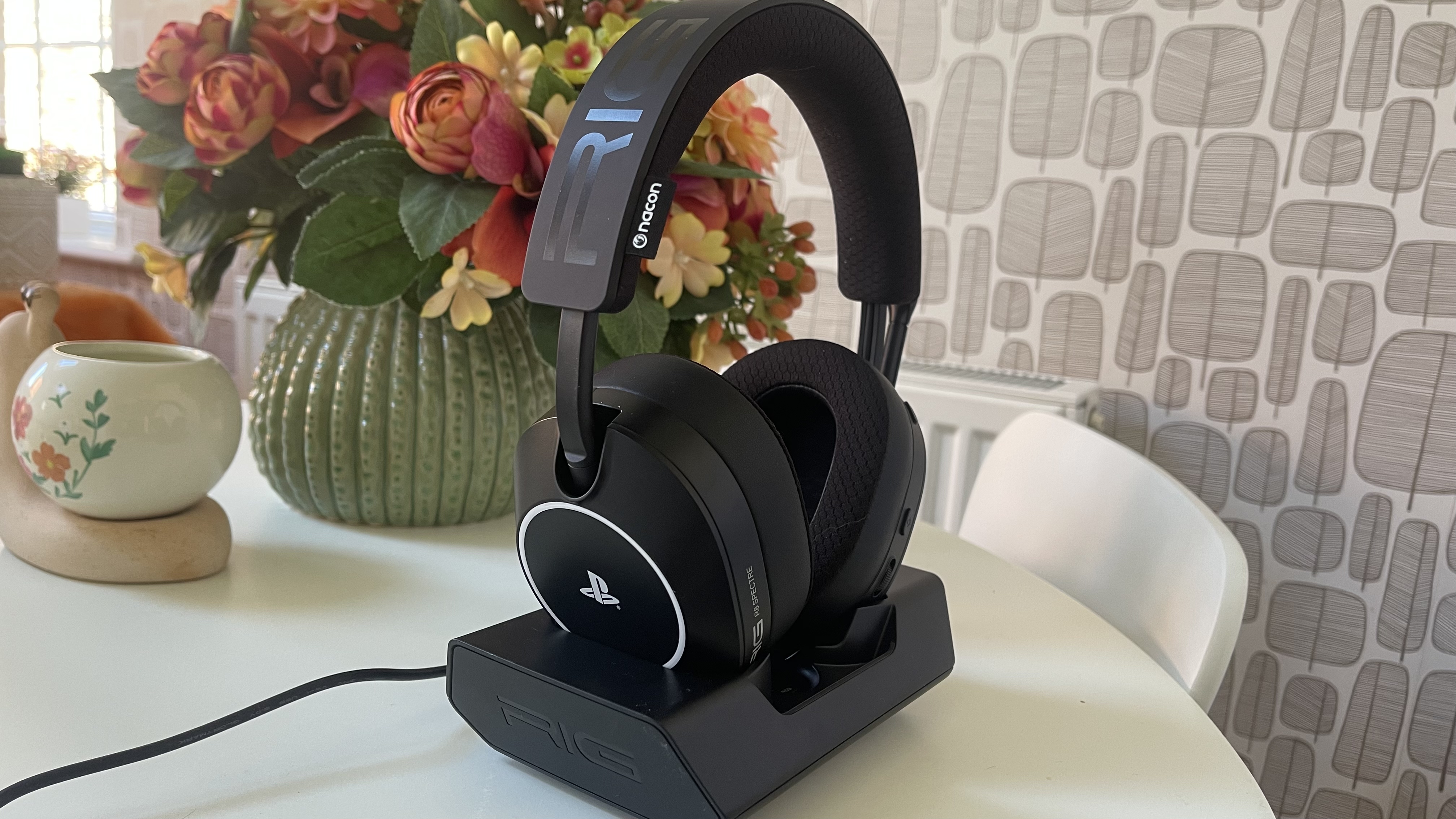 The RIG R8 PRO HS gaming headset on its base station sitting on a light coloured table