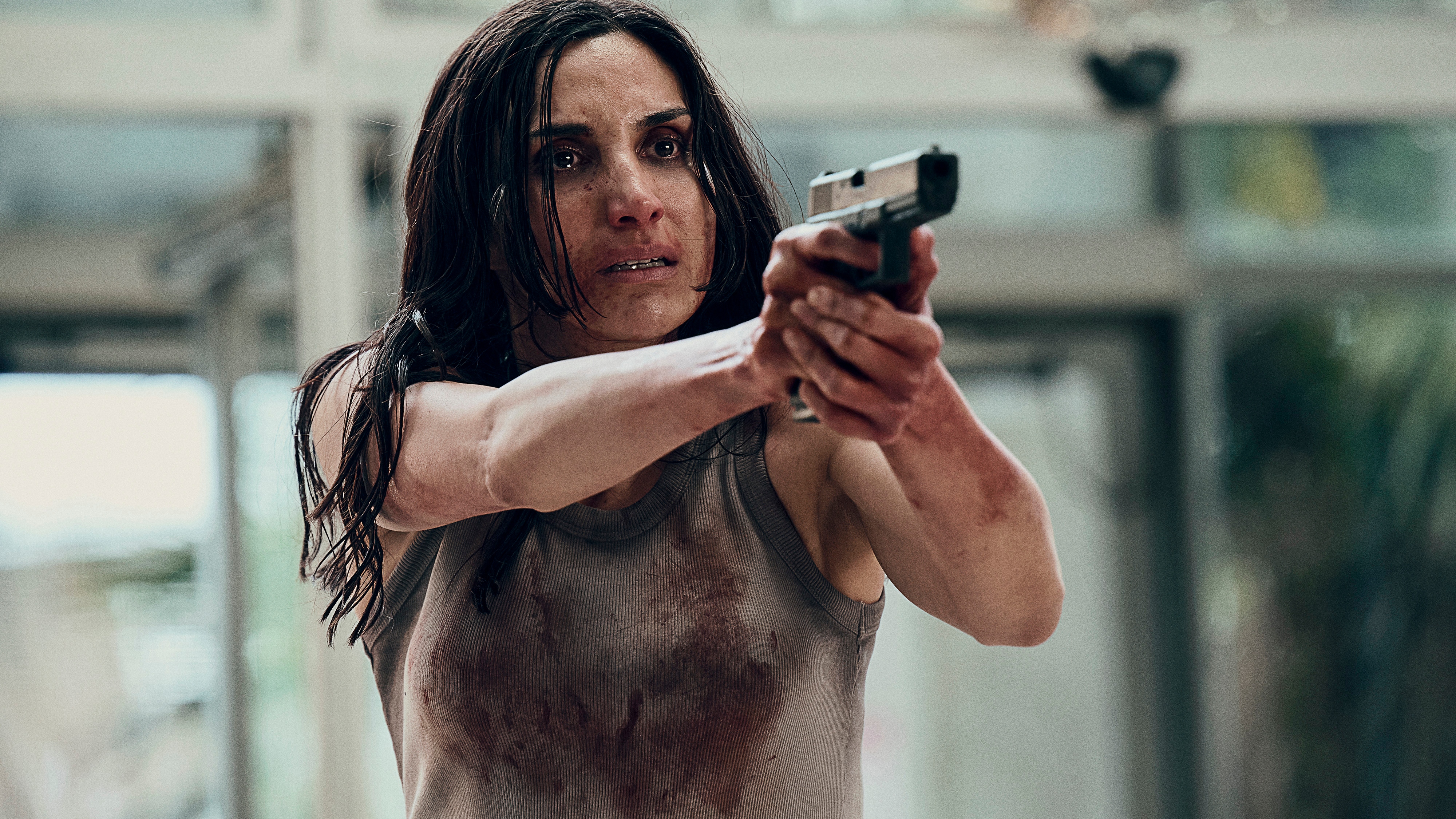 Lale covered in blood and pointing a gun in Gangs of London season 3.