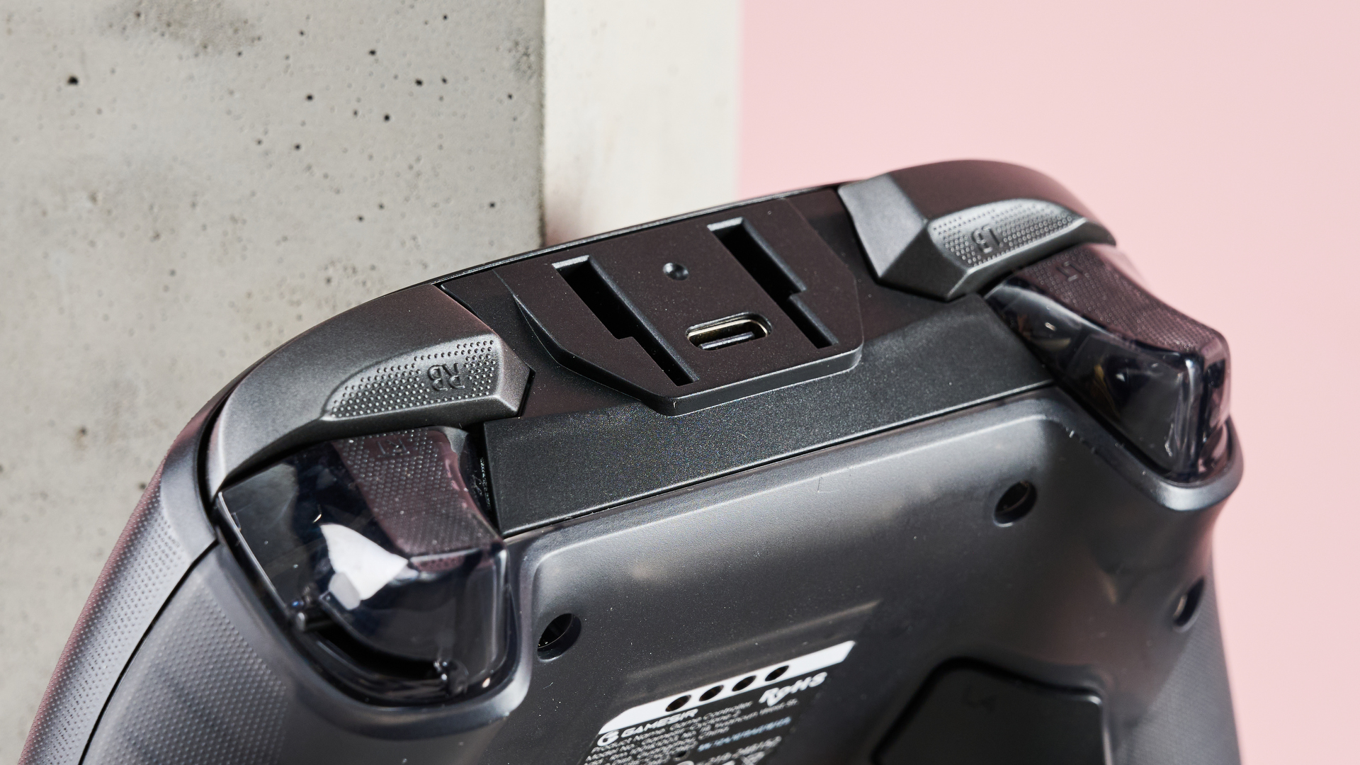 Close-up of shoulder buttons on GameSir Cyclone 2 with plinth and pink wall in background