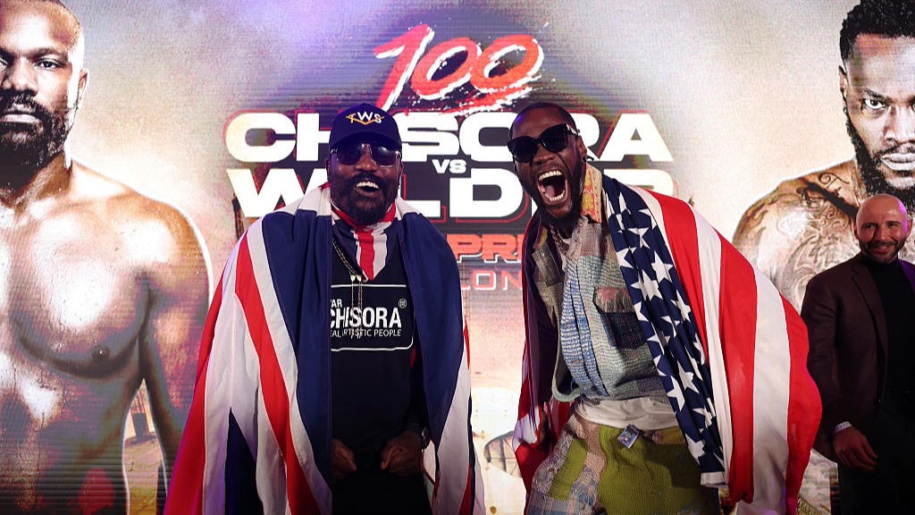 Derek Chisora, wearing a Union flag, and Deontay Wilder, draped in an American flag, pose ahead of their fight at the O2 Arena, London.