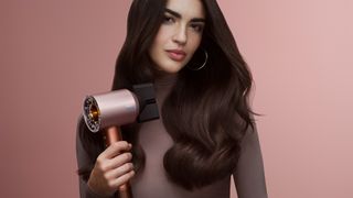 Woman using Dyson hair styler in Amber Silk colorway