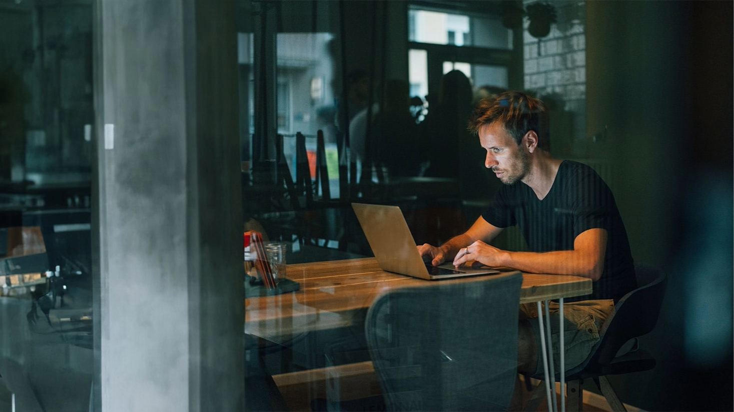 A man in the dark looking at his laptop
