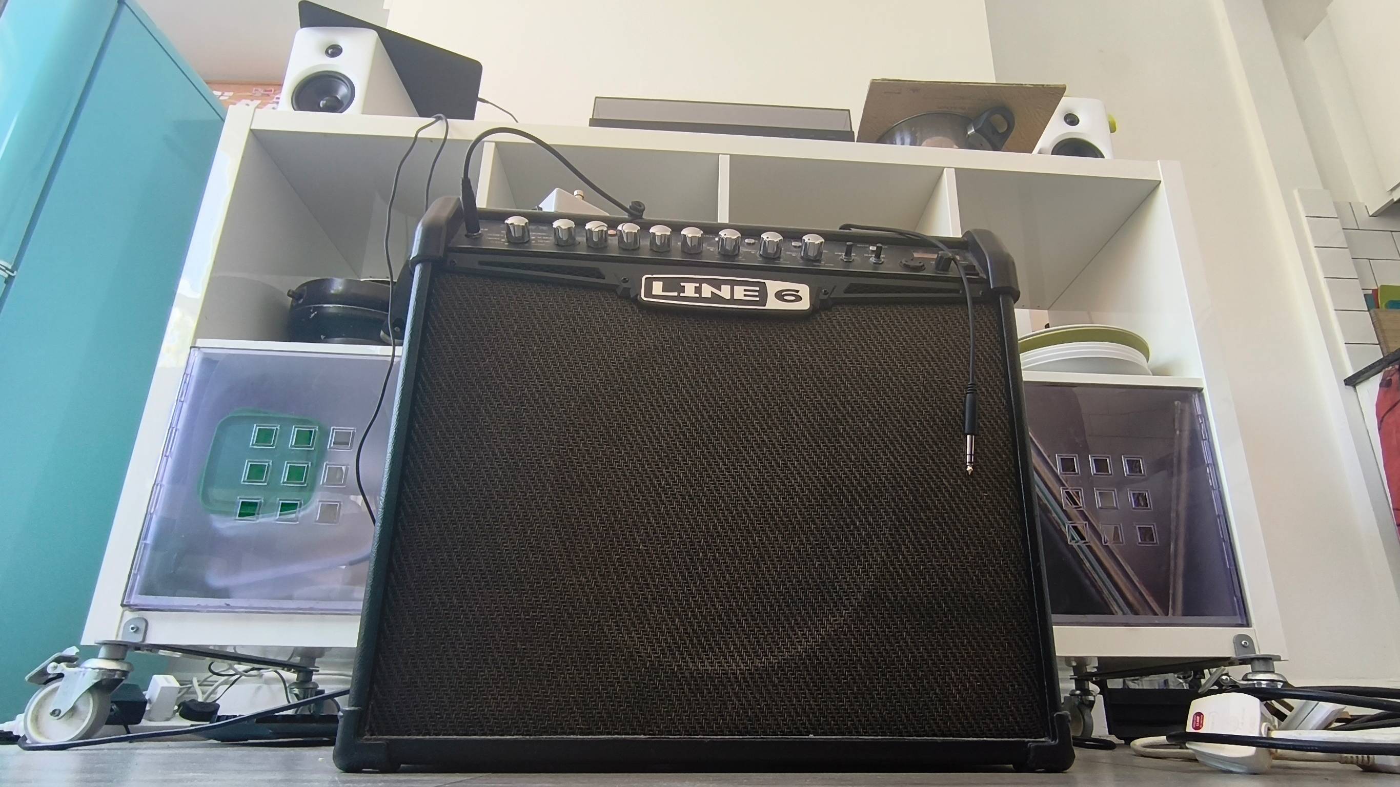 The Line 6 Spider IV amp in front of a cabinet with some Edifier speakers.
