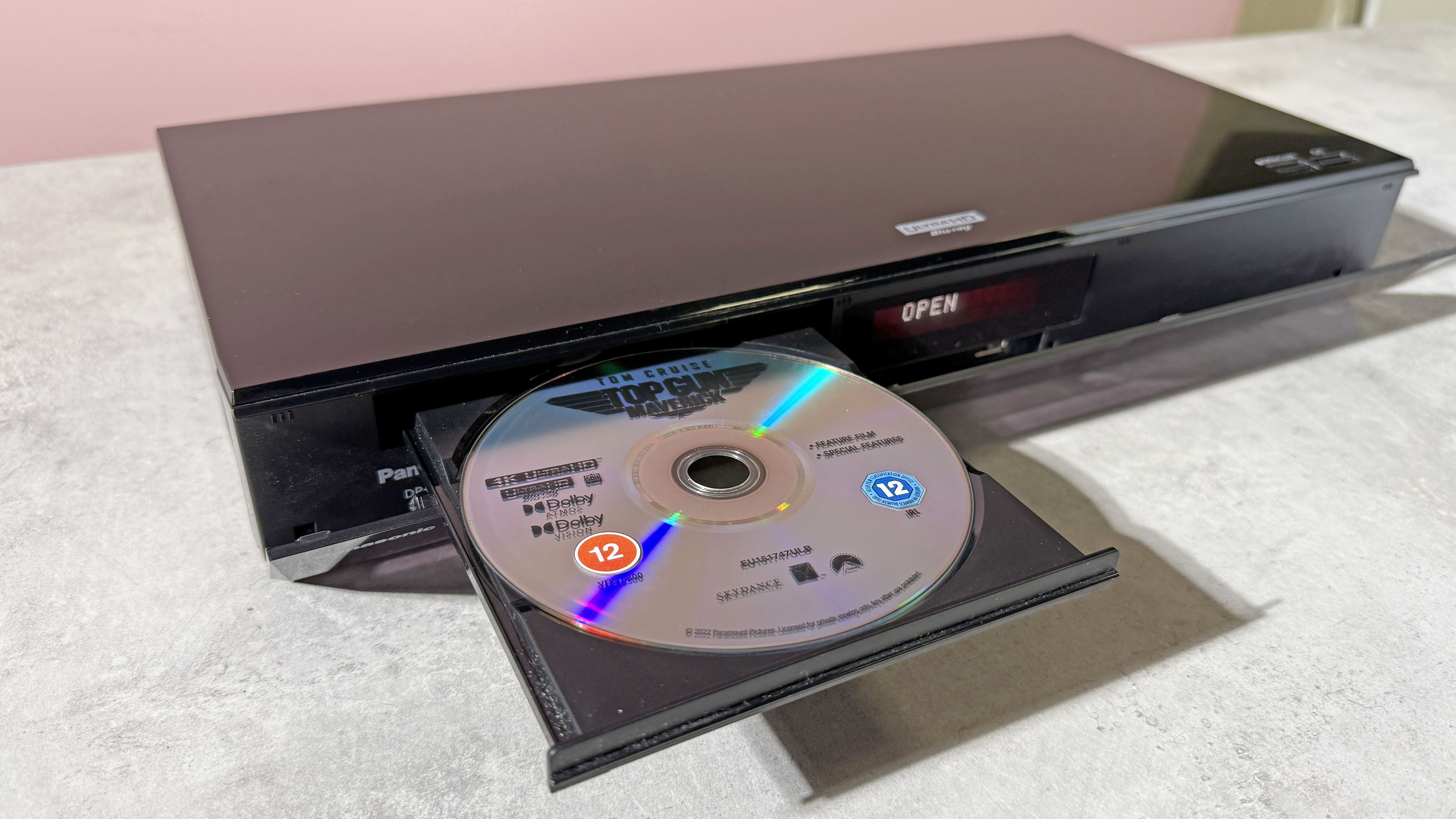 A Panasonic DP-UB820 4K Blu-ray player, with its disc tray open, and copy of Top Gun Maverick on 4K Blu-ray disc in the tray