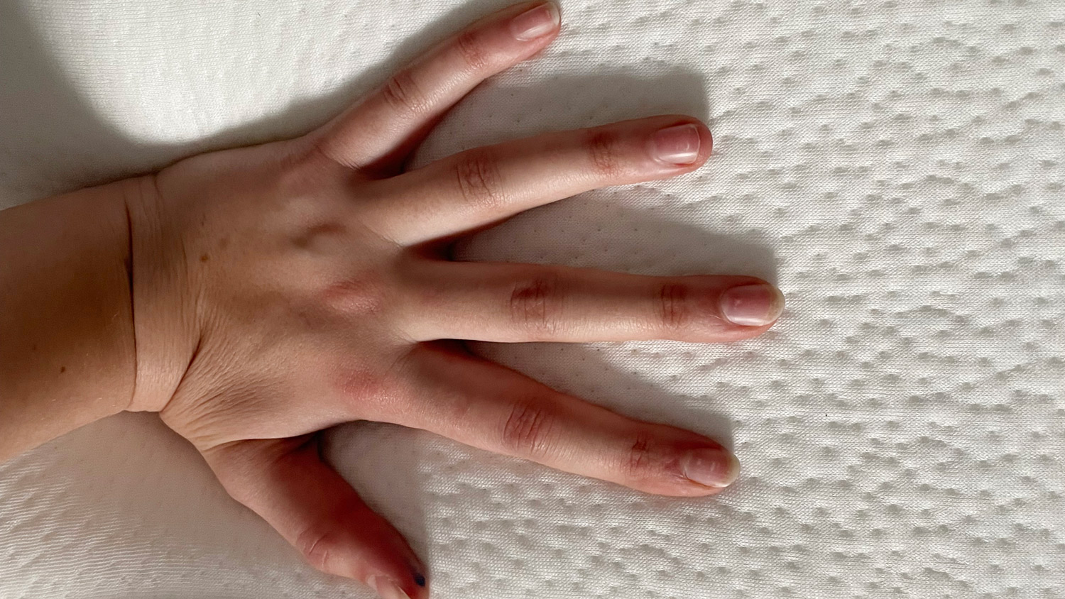 A hand pressing on the Origin Hybrid Mattress