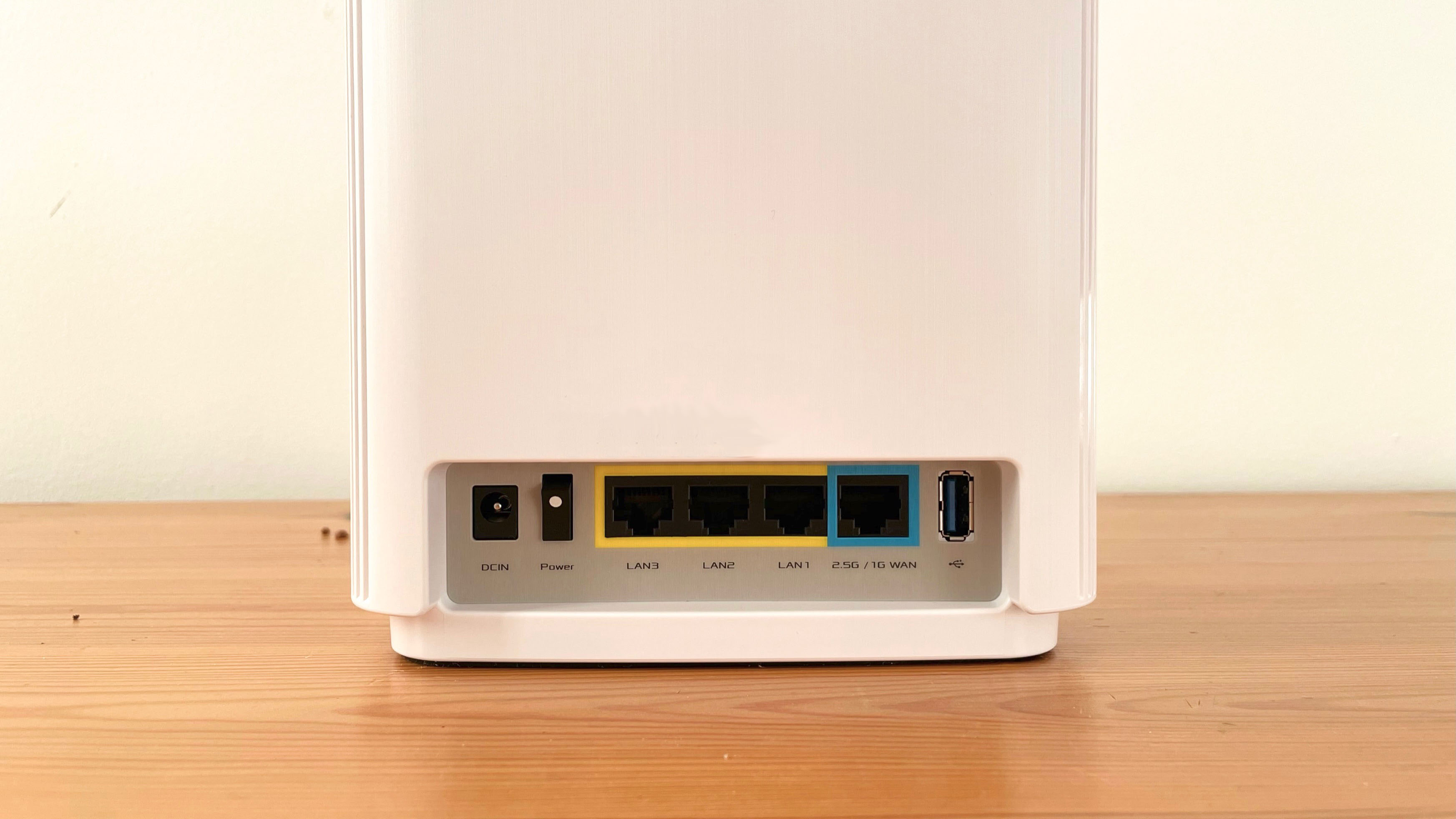 Asus ZenWifi XT9 product review images on a wooden desk