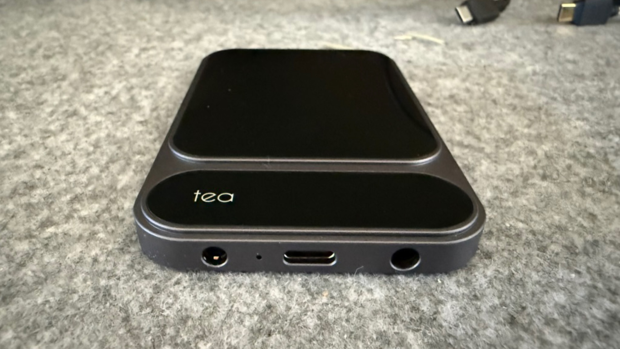 Photograph of the Khadas Tea Pro Headphone Amplifier on a grey fabric surface