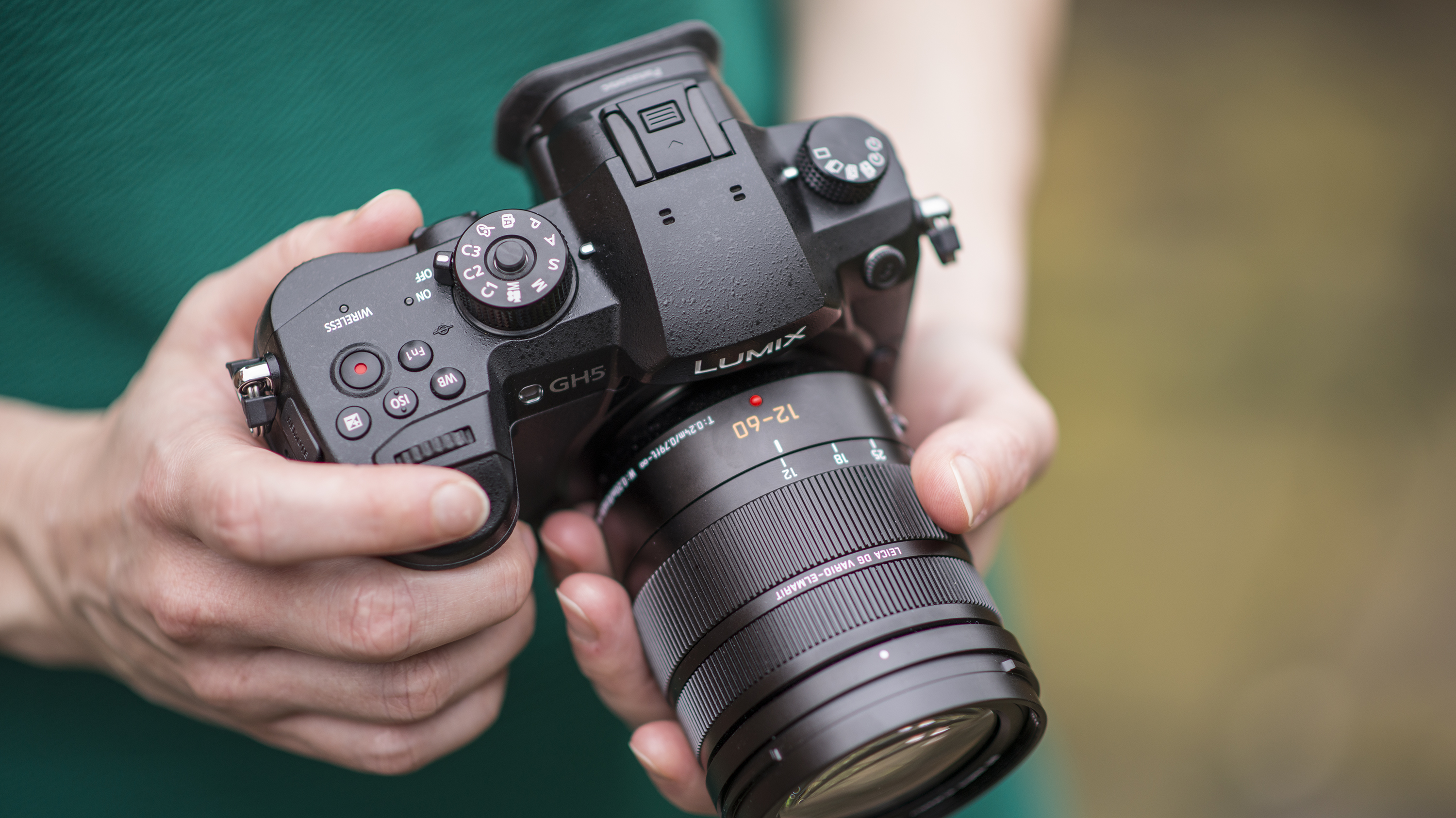 Panasonic Lumix GH5 camera with 12-60mm lens attached, in user's hands